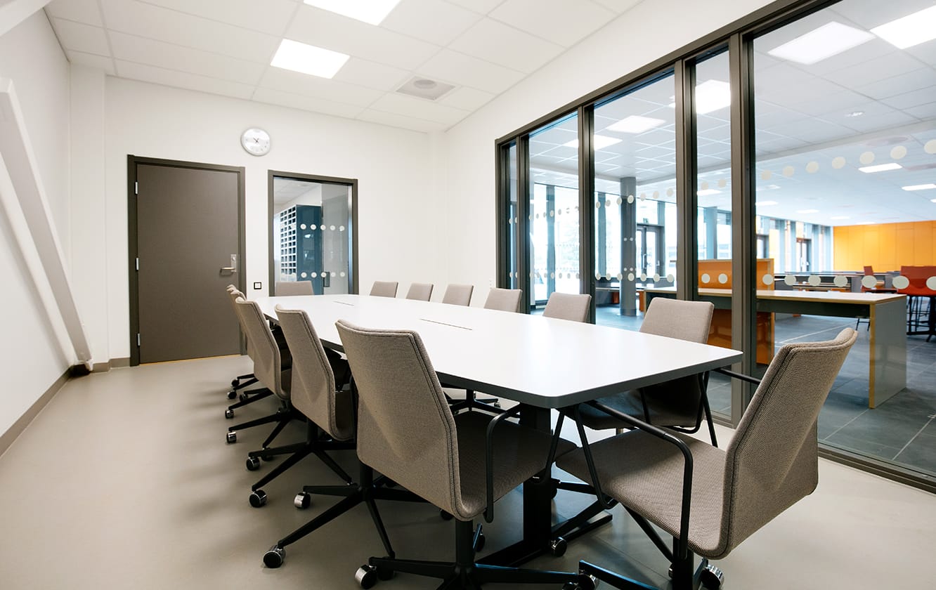 A conference room with a large conference table and office desk chairs.