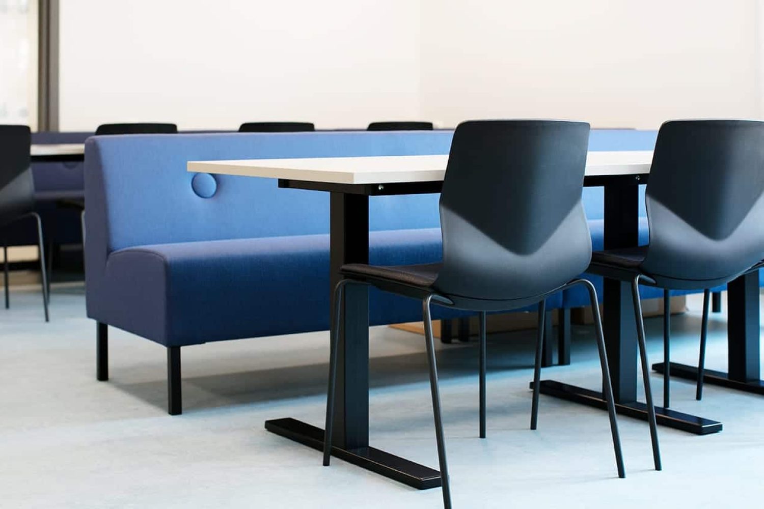 A group of chairs and office tables in a room with a blue office sofa.