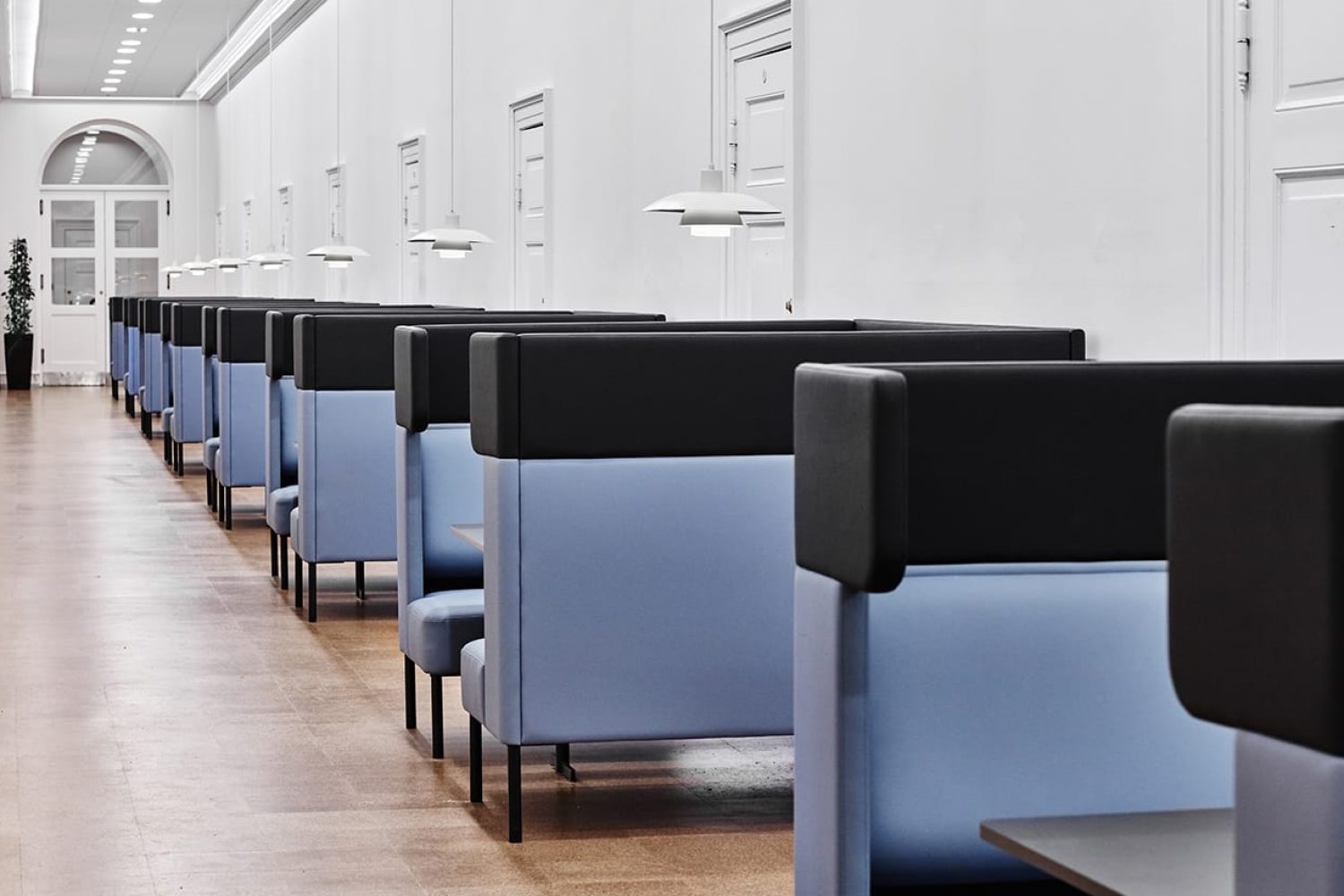 A row of blue and black office work booths in a hallway.