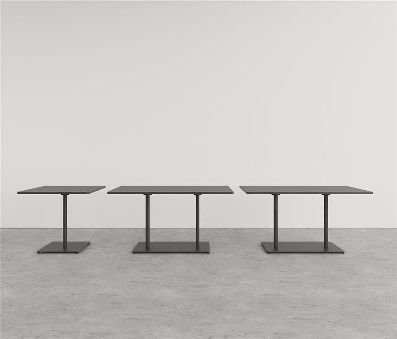 Three black pedestal tables in front of a white wall.