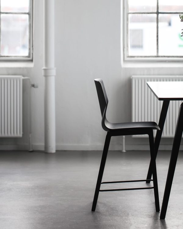 A dining table with two black counter height chairs in front of a window.