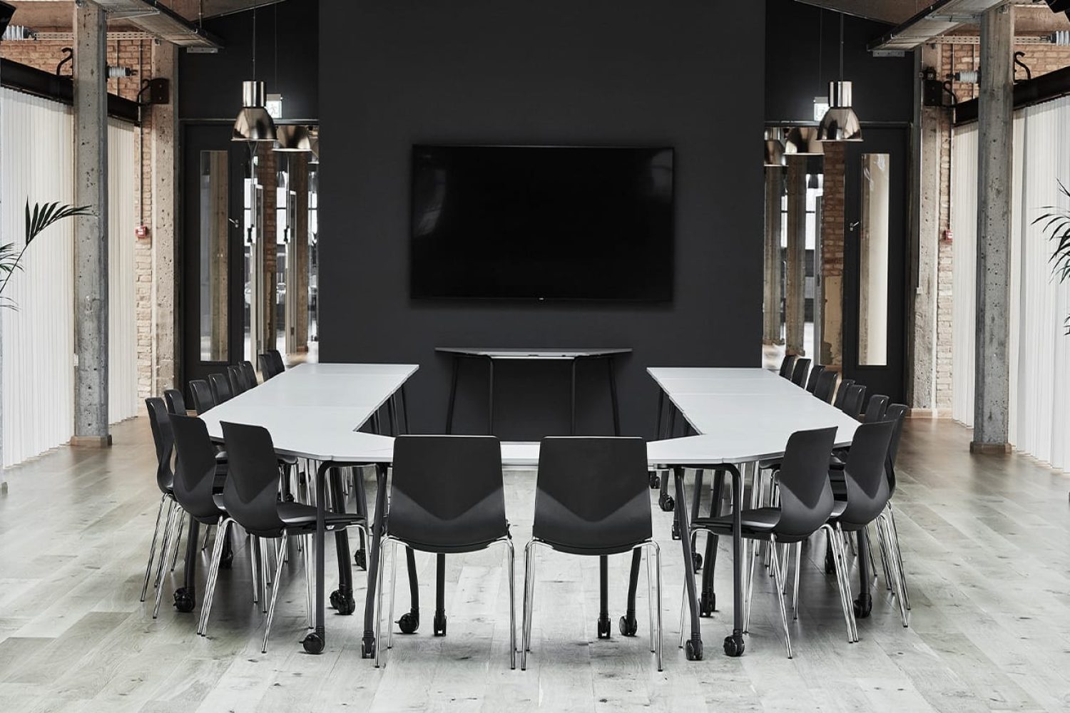 A black and white conference room with tables and office desk chairs.