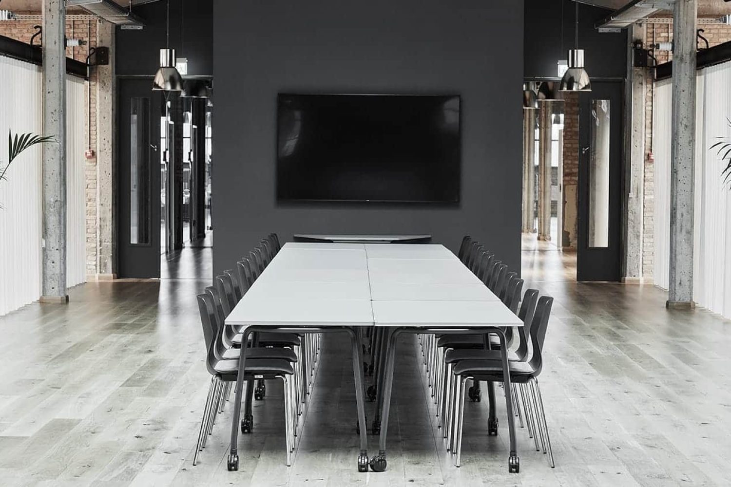 A black and white conference room with tables and office desk chairs.