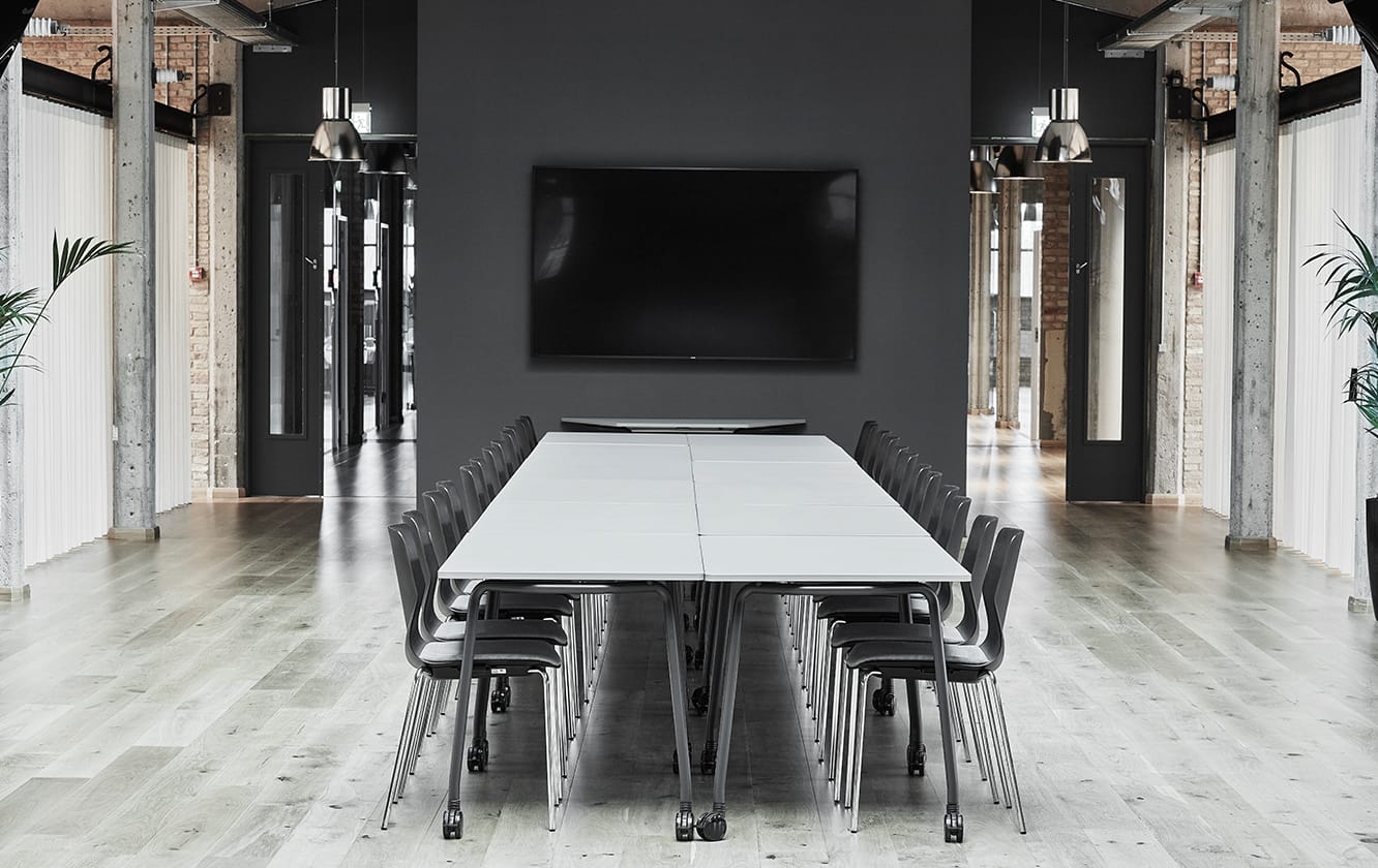 A black and white conference room with tables and office desk chairs.