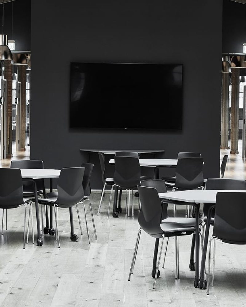 A black and white conference room with tables and office desk chairs.