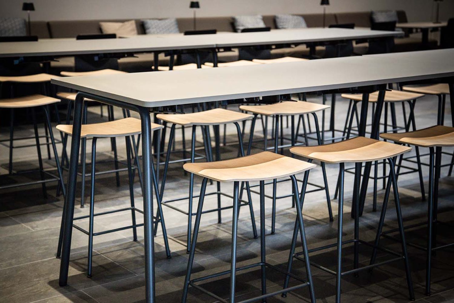 A group of office stools and counter height tables in a conference room.