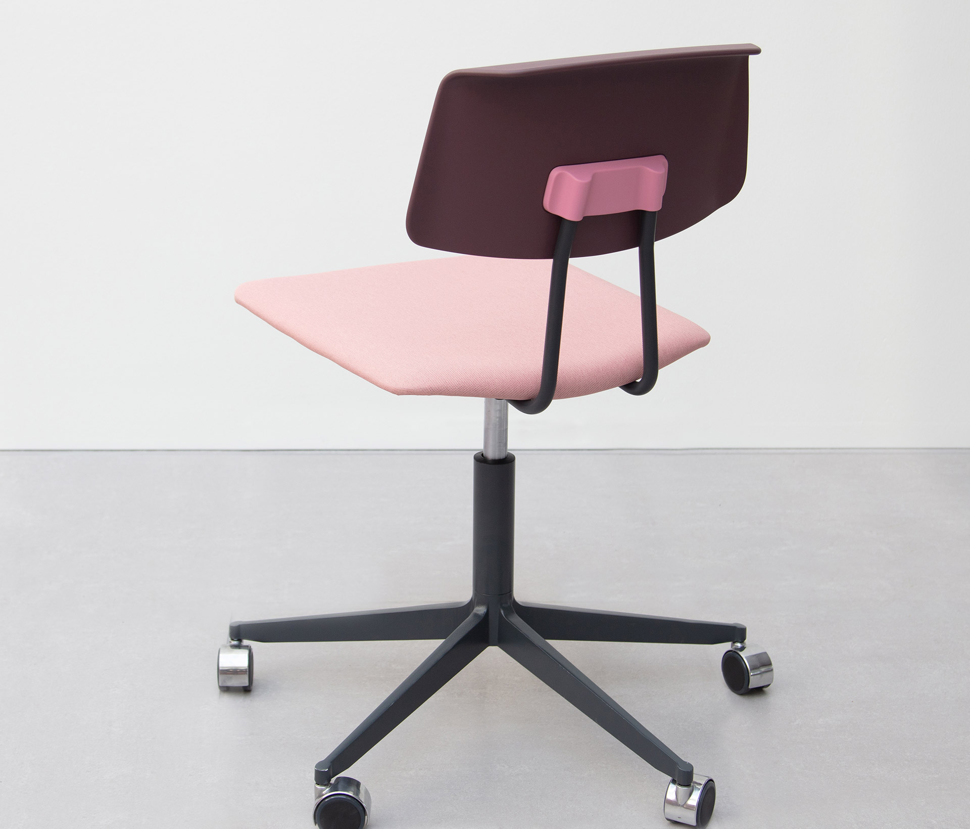 A pink office chair with a black seat and wheels.