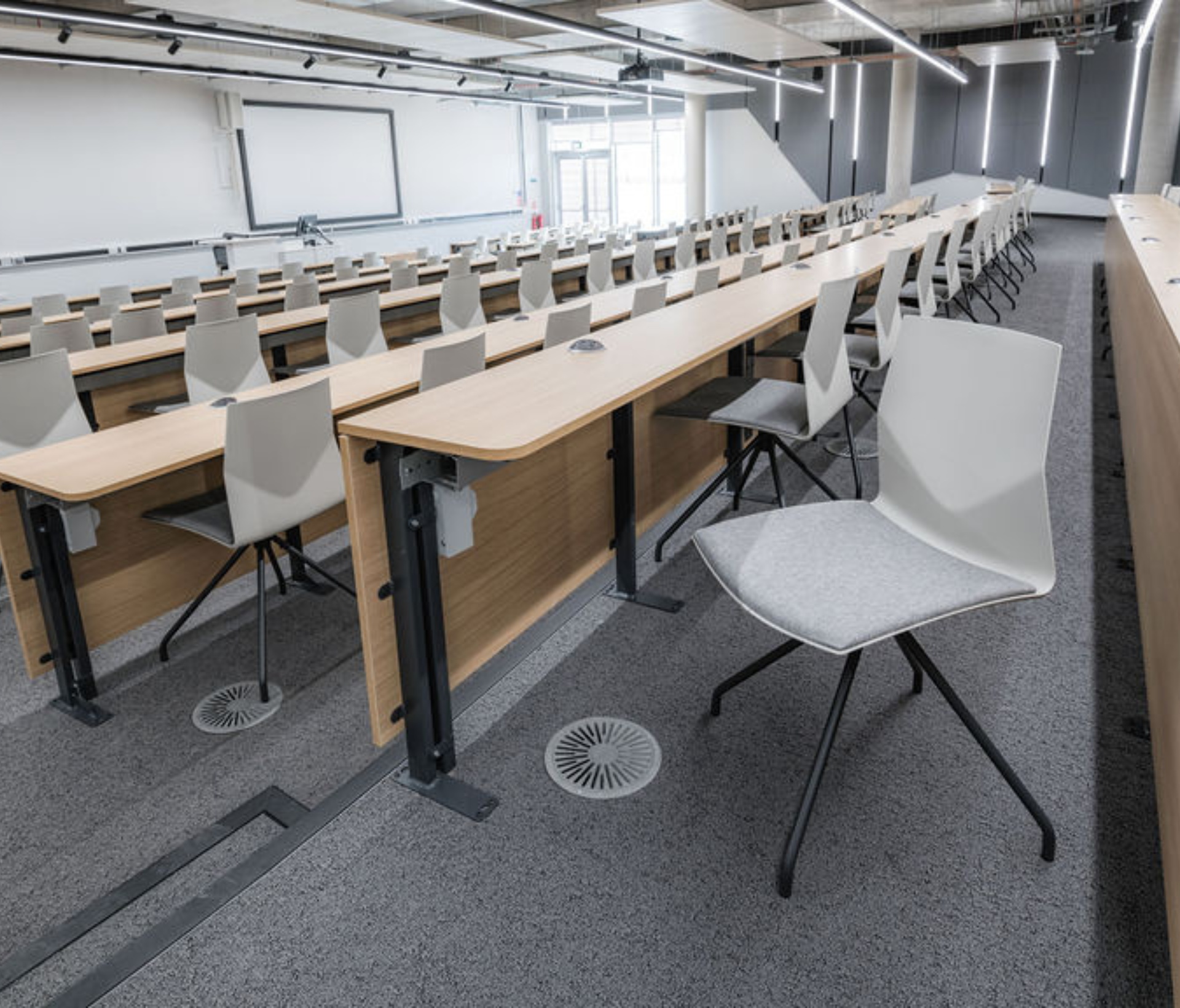 An empty lecture hall with chairs and a projector full of Ocee and Four Design office furniture at the University of Sheffield