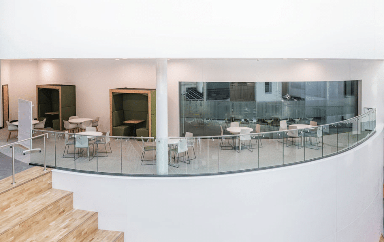 A white building with a circular staircase and Ocee and Four Design tables in the University of Sheffield