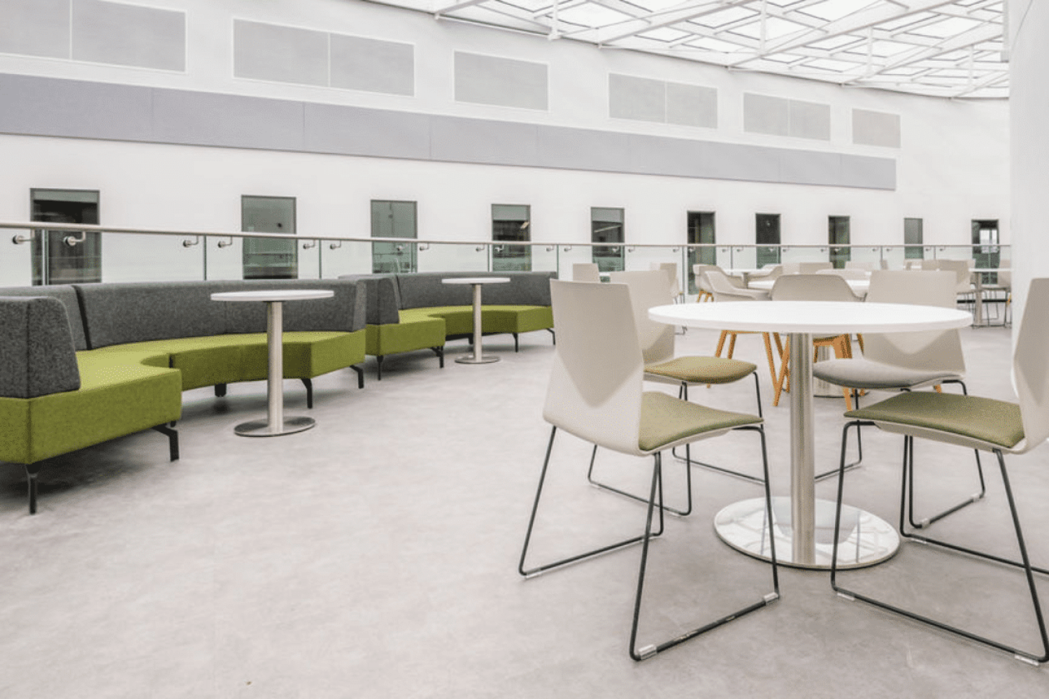 A modern office full of Ocee and Four Design office furniture with tables and chairs and a glass roof at the University of Sheffield