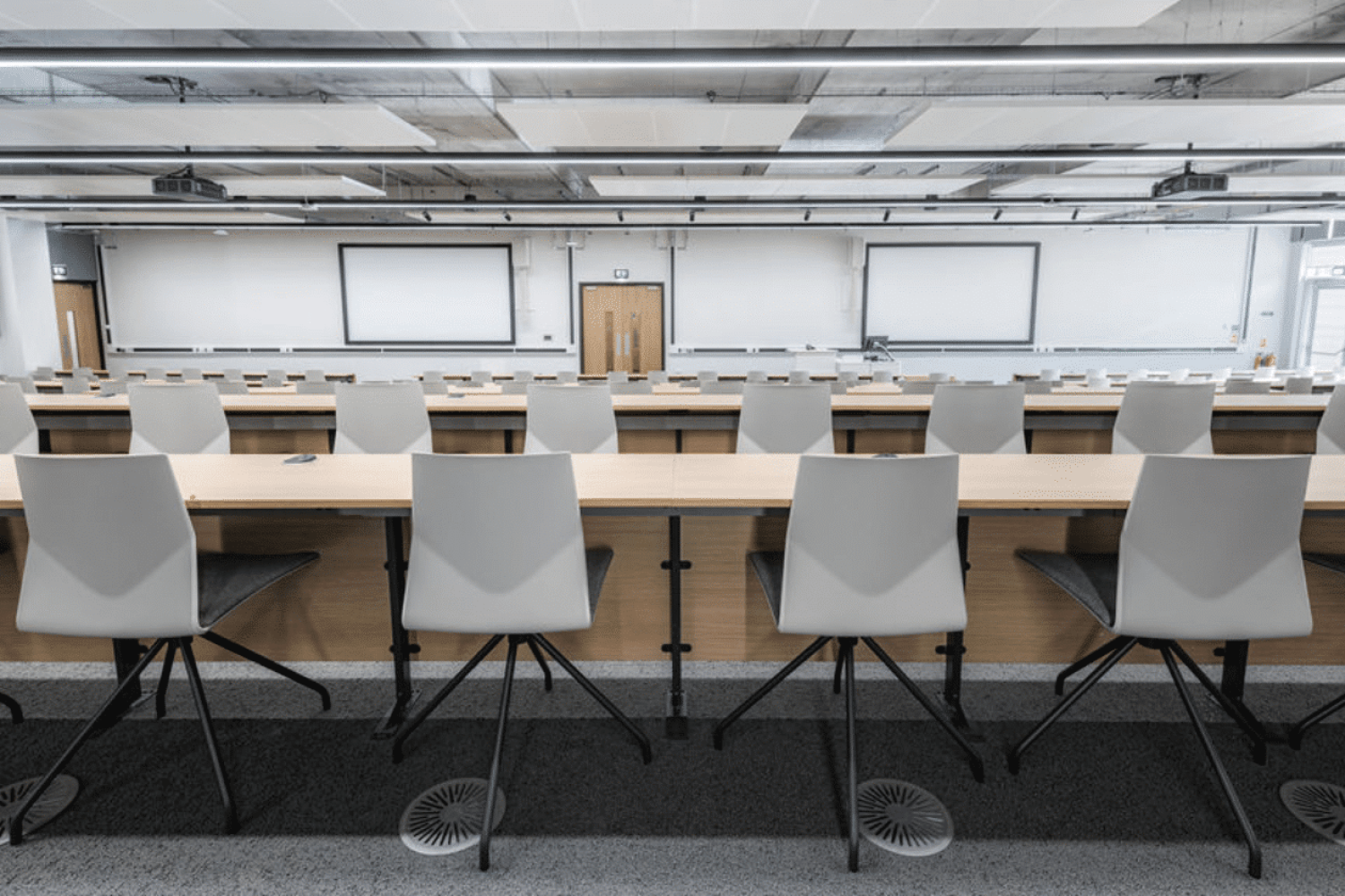 An empty lecture hall with office desk chairs and a projector in the University of Sheffield