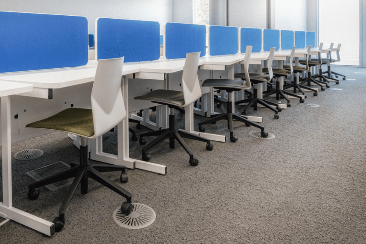 A row of desks in study booths an office with blue screens at the University of Sheffield