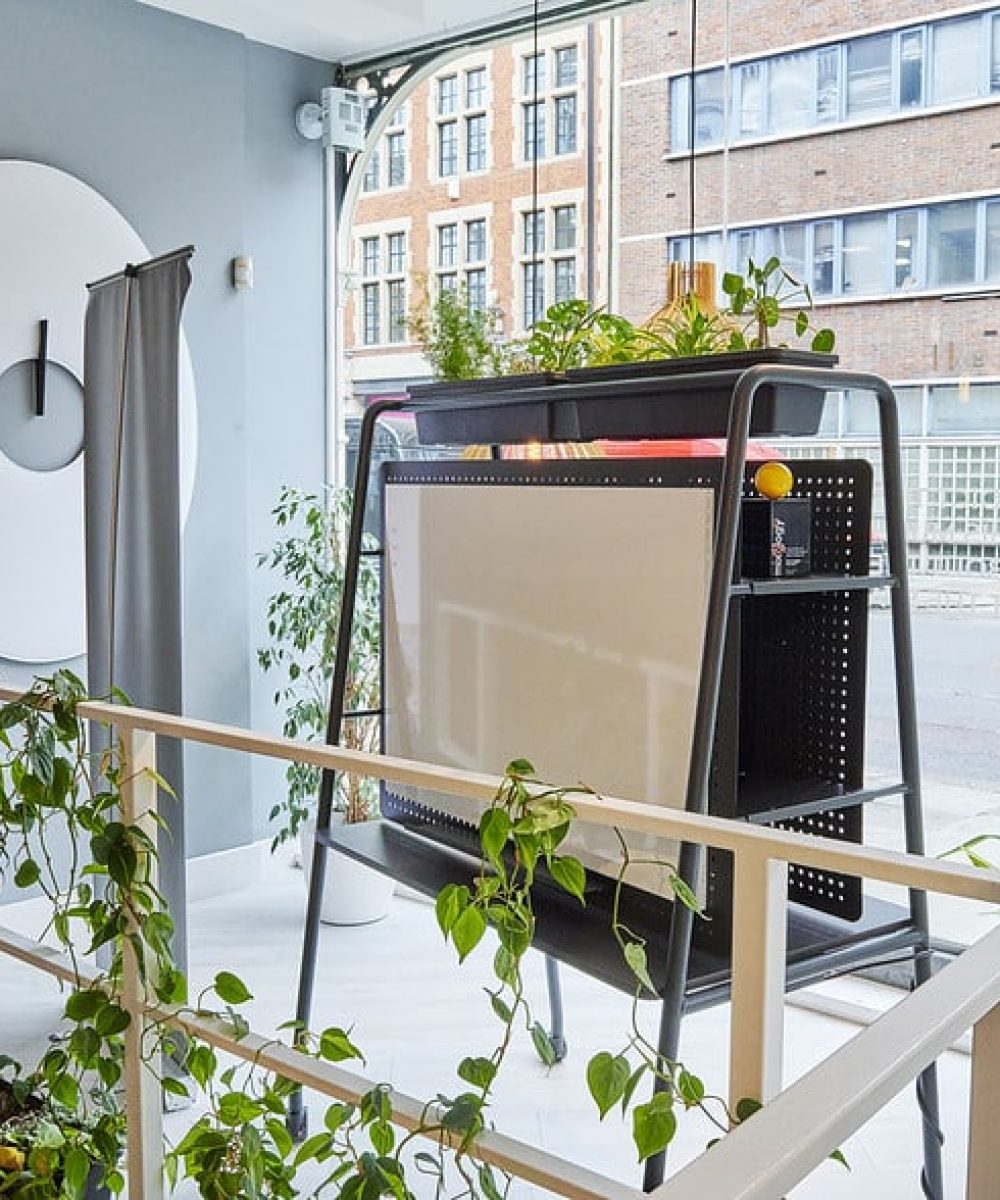 A room with plants and FourReal AV community tables in it.