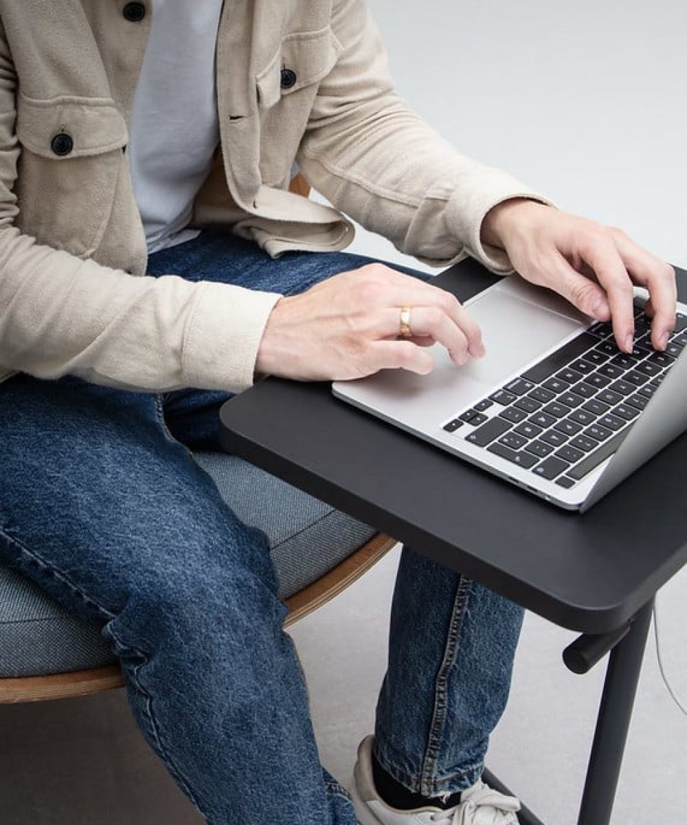 A man on a chair using a laptop on a Y-table adjustable height work table.