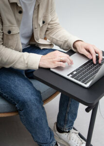 A man on a chair using a laptop on a Y-table adjustable height work table.