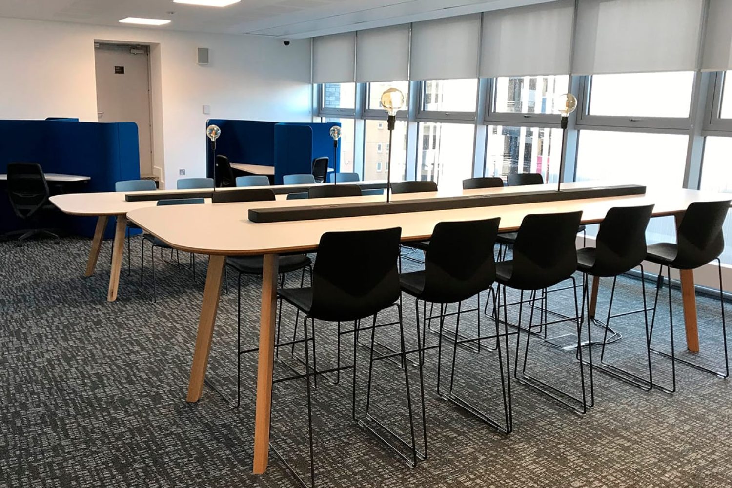 A conference room with a standing height table and counter chairs.