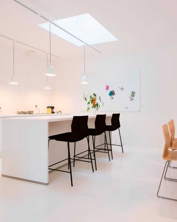 A white kitchen with counter height tables and chairs.