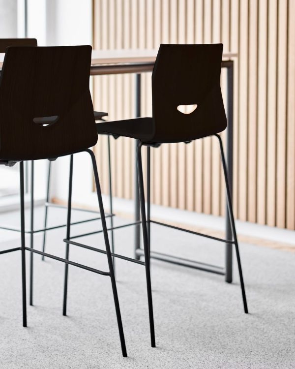 Four black counter chairs in an office with a wooden table.