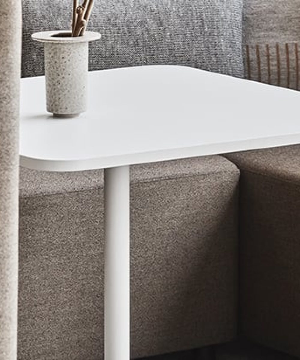 A small white pedestal table next to a couch.