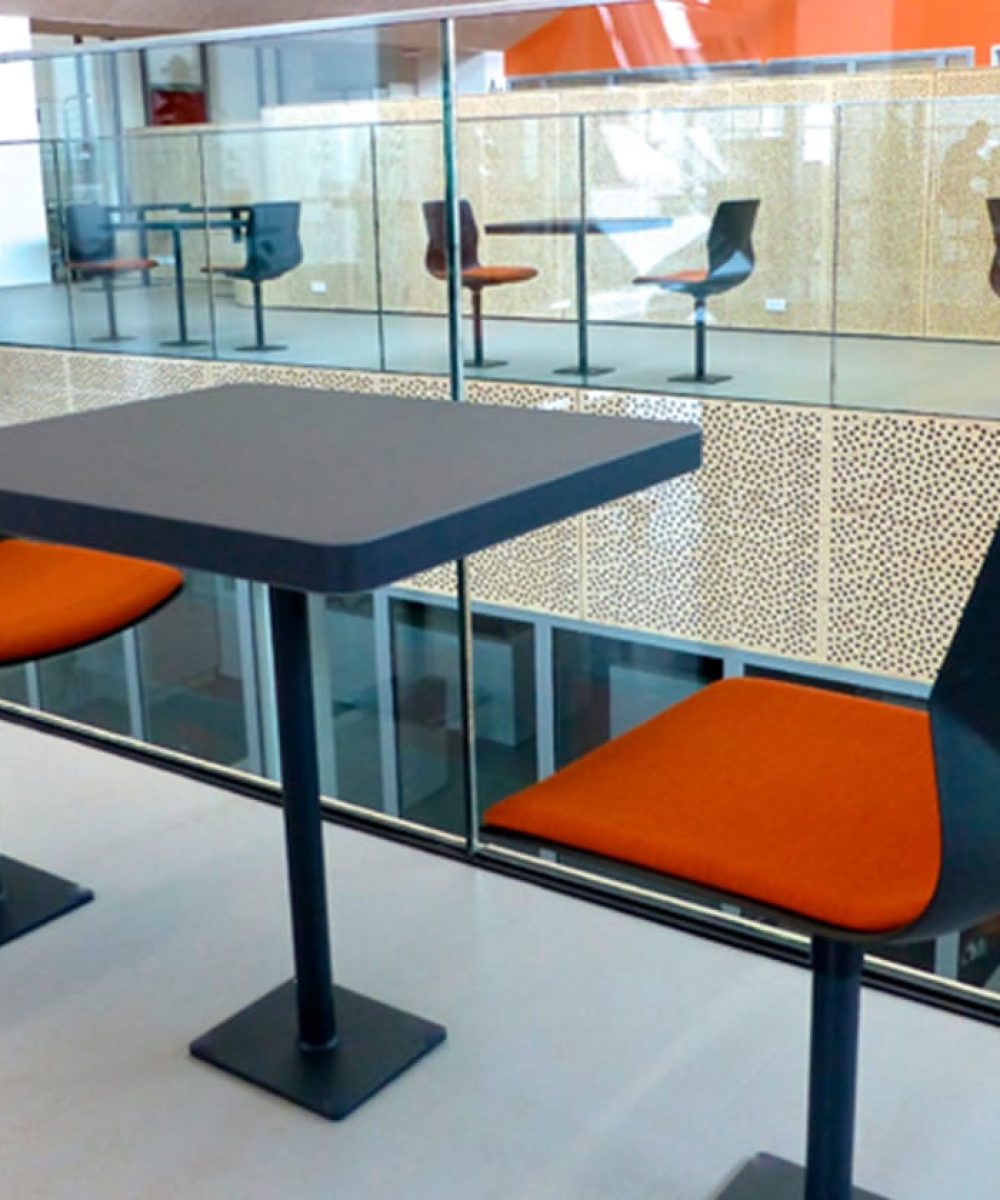 An orange and black table and chairs in a glass building.