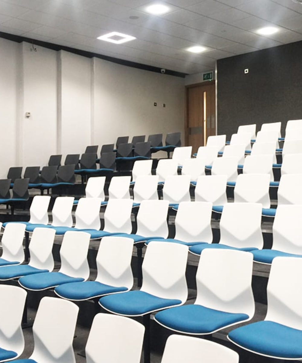 A lecture hall with rows of chairs and blue seats.