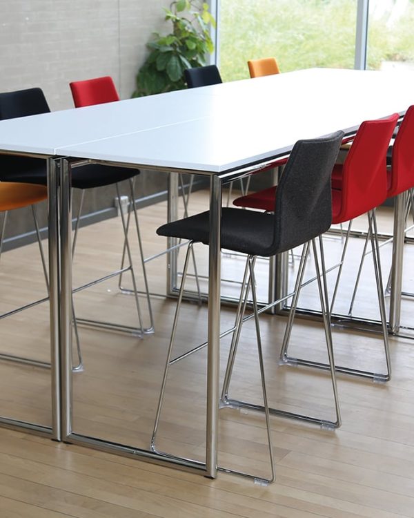 A white conference standing height table with counter chairs in front of it.