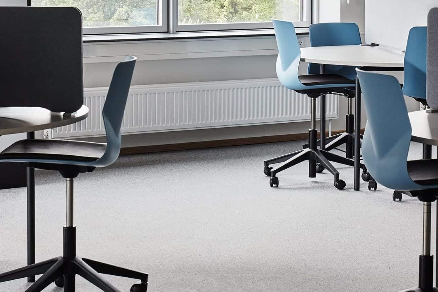 Desks and office desk chairs in a classroom with a window.