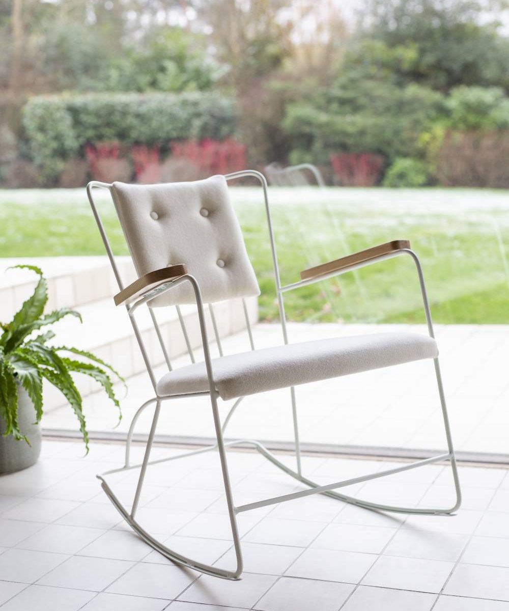 A white rocking chair on a tiled patio.