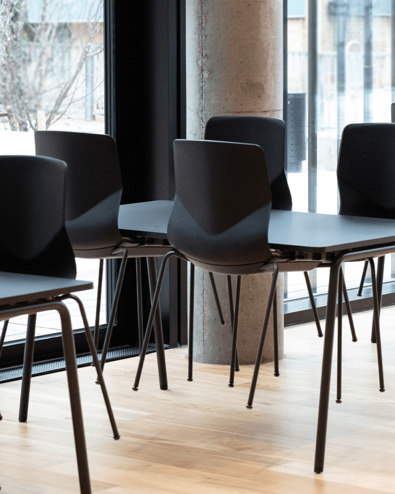 A row of black chairs and tables in a room.