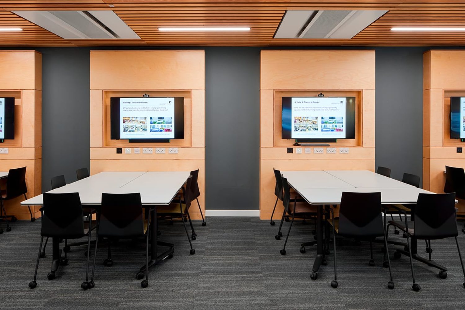 A conference room with tables and tv screens.