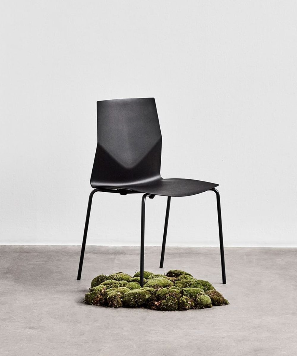 A black chair with moss underneath it