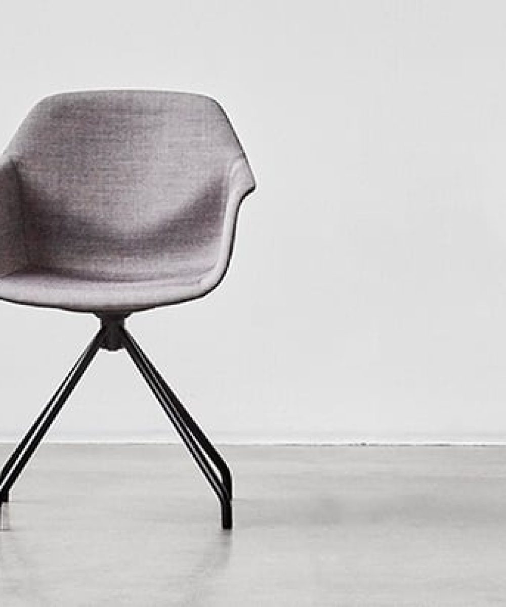 A gray chair with black legs in a white room.