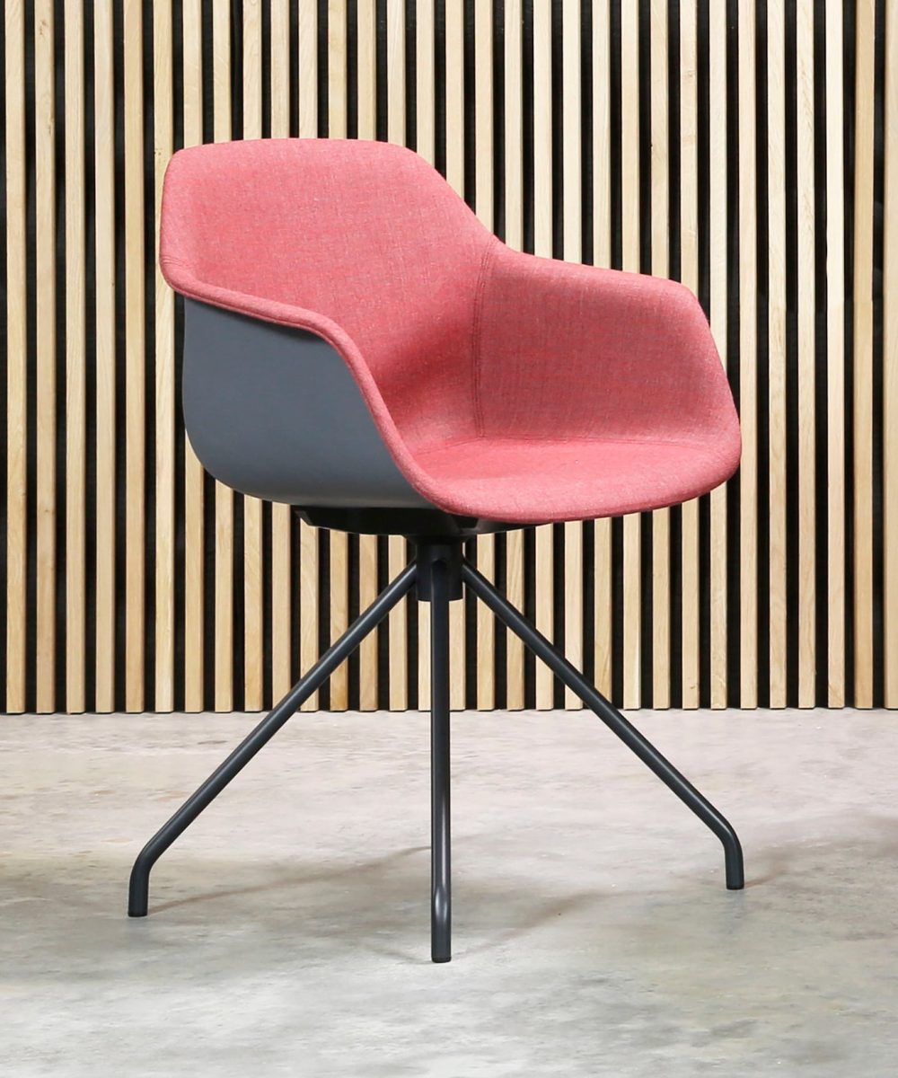 A chair with a pink upholstered seat in front of a wooden wall.