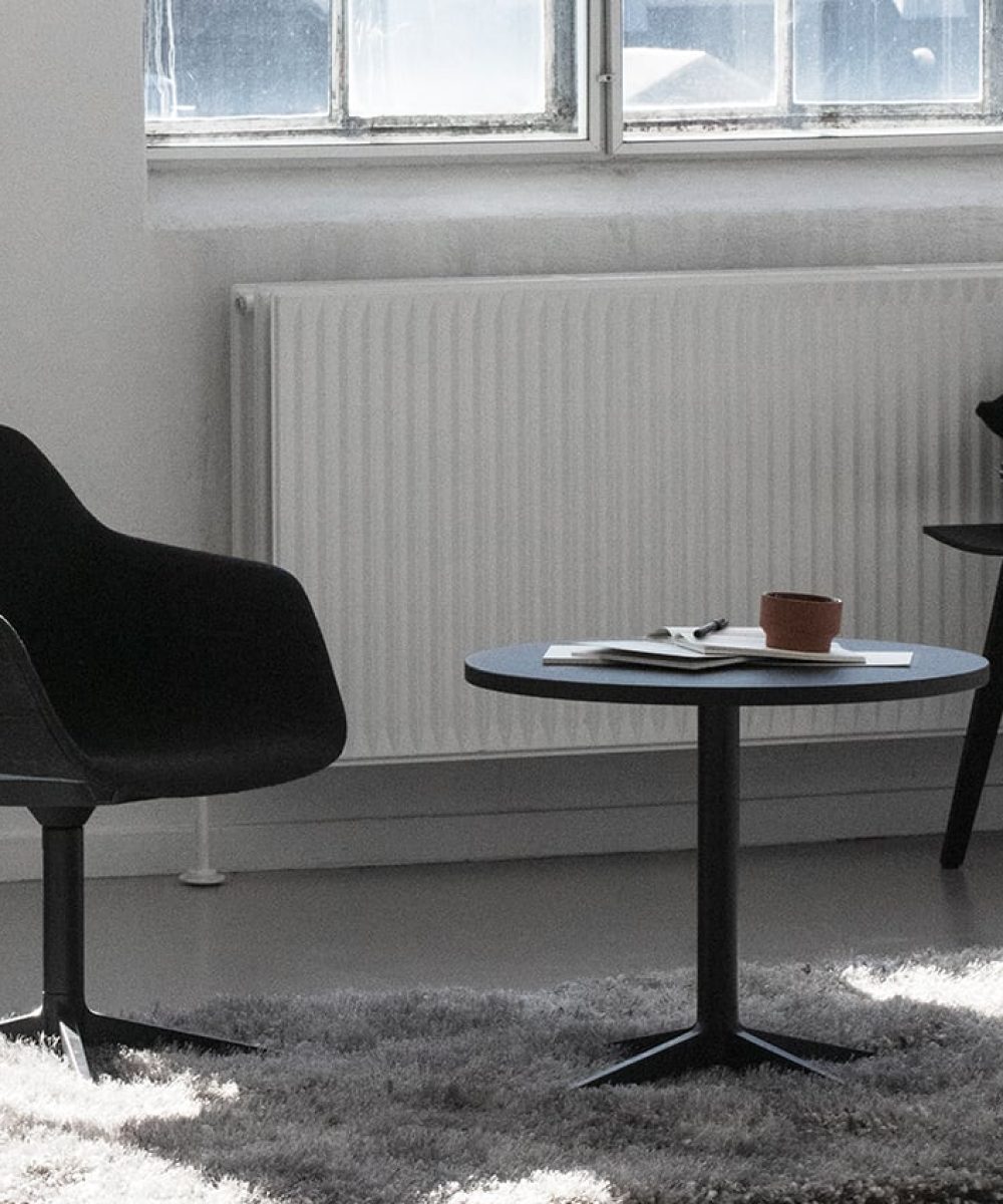A black chair and table in a room with a window.