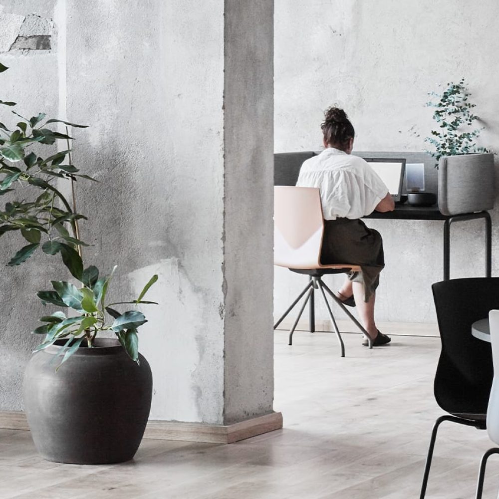 A woman sits at a desk workstation in an office.