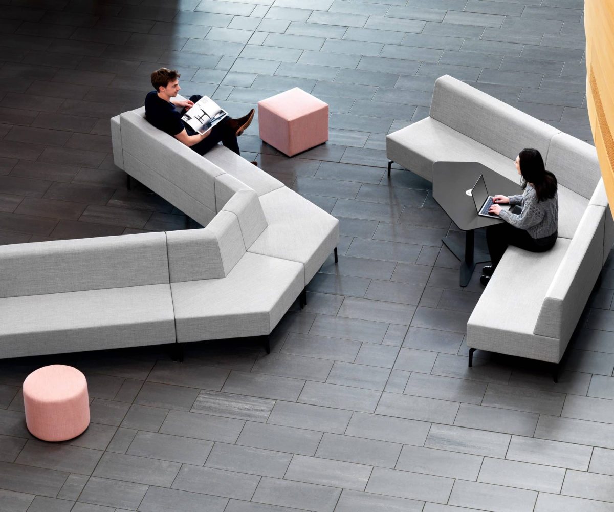 An office with a grey modular seating office sofas with pink ottoman office stools.